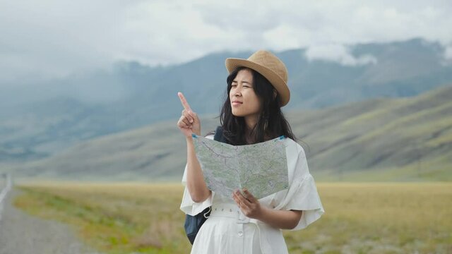 Young woman travelling with paper map, she is choosing her way, looking around.