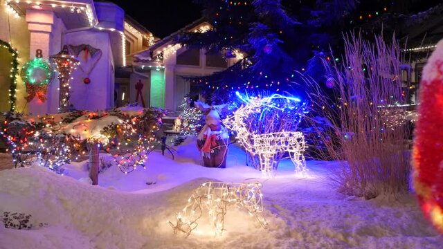 Christmas displays on snow covered front yards of houses