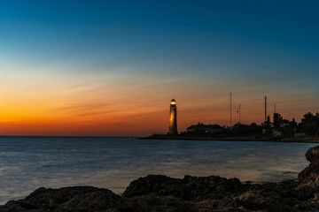 Romantic view of the lighthouse from the cliff at sunset