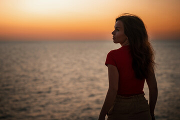 Silhouette of a slender young woman at sunset on the sea