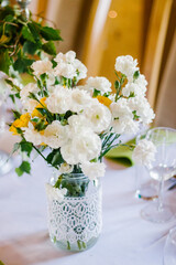 bouquet of white carnations in a jar decorated with white lace standing on the holiday table