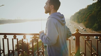 Active lifestyle. Profile of sporty man running on city bridge early in morning, slow motion