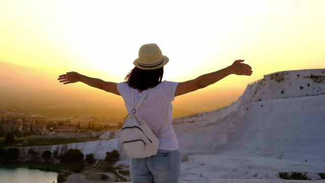 The tourist woman turns in slow motion with her arms open in the uniquely beautiful Pamukkale travertine. Travel Concept.