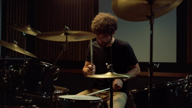 Gloomy drummer throwing drumsticks in studio. Upset artist leaving concert hall.