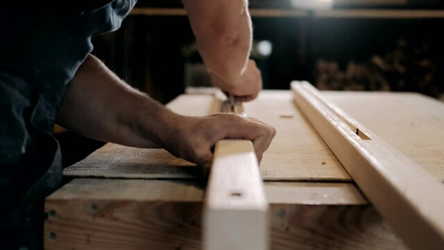 Close up shot of carpenter or joiner sanding wooden plank with sanding paper in wood workshop. Carpentry, craftsmanship, Handicrafts.