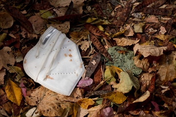 Waste during COVID-19. Discarded to single-use coronavirus masks. Environmental pollution, on dry leaves