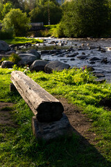 Rocky river in city park in autumn with a log bench, vertical