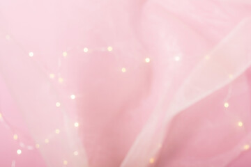 Blurred background of pink paper covered with artificial transparent silk, draped fabric with...