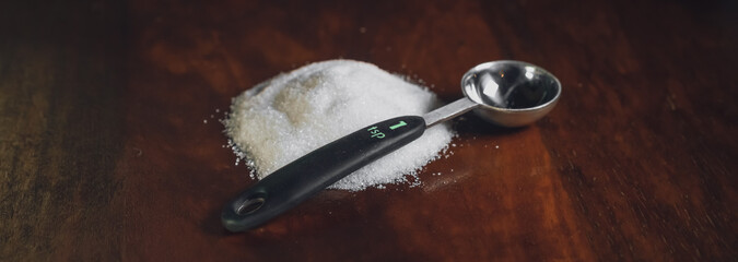 a pile of sugar on a table beside a 1 teaspoon measuring spoon