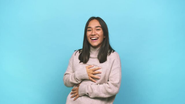 Young mixed race indian woman laughs happily and has fun keeping hands on stomach