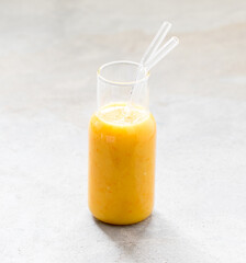 Drink cocktail yellow tomato in a glass bottle with a straw on a light background