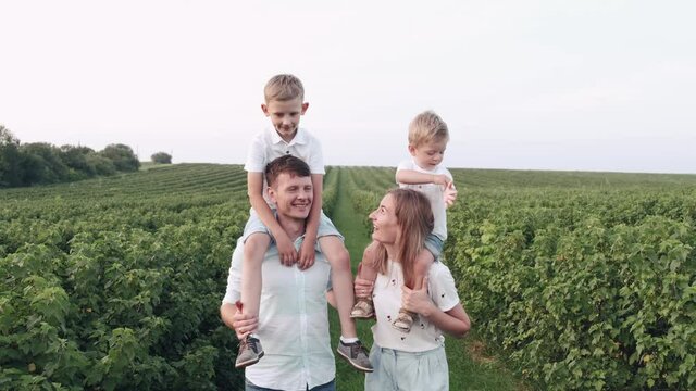 Family with kids are having fun outside. The little sons are playing and smiling. The parents are excited.