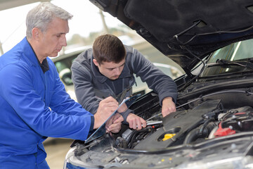 student with instructor repairing a car during apprenticeship