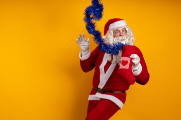 Emotional male actor in a costume of Santa Claus holds in his hands a Christmas sock with gifts and...