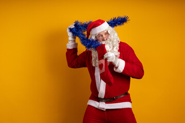 Emotional male actor in a costume of Santa Claus holds in his hands a Christmas sock with gifts and...