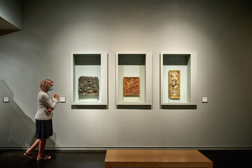 woman stading in a room looking and pointing at the empty frames displayed