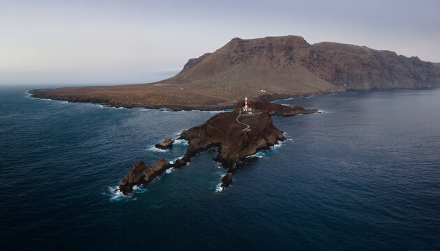 Aerial view of the Punta de Teno lighthouse in the far west of the Atlantic island of Tenerife after sunset. In the background are the mountains and on the right the high cliffs of Los Gigantes.