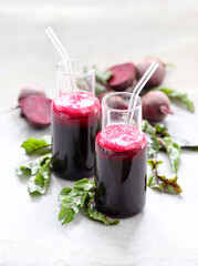 Beetroot drink cocktail in a glass bottle with a straw on a light gray background