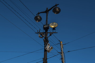 Old vintage black decorative lantern with glass on pillars. Three street lamps on two pole in sun...