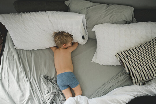 Boy napping in parent's bed in boxer briefs