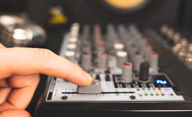 Sound engineer using main control fader of studio mixer.