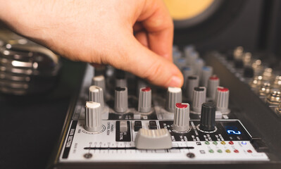 Fototapeta na wymiar Sound engineer using control channels of studio mixer.