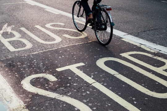 Person riding bicycles in London over the BUS STOP sign