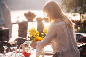 Blonde young woman setting up the dinner table