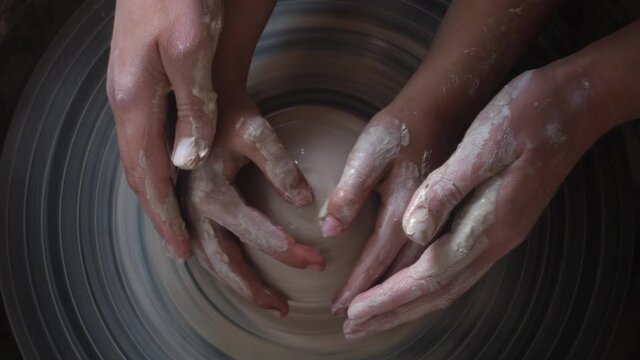 Hands of Little Girl making ceramic pot and Expert Potter Ceramist teaches her. Modern Handmade Ceramics. Concepts of: experience, art, tradition, family.
