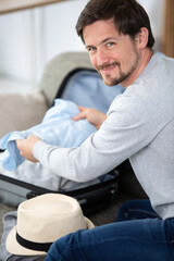 man packing his shirts in suitcase for business travel