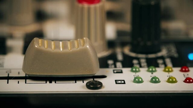 Sound engineer using main control fader of studio mixer.