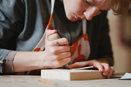 Caucasian woman carves wooden cliche