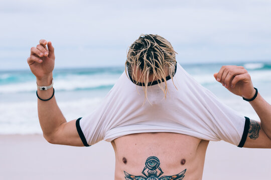 Young man putting on his shirt