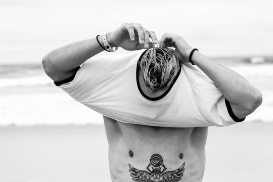 Young man putting on his shirt