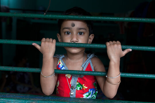 Little girl behing the window and looking at camera