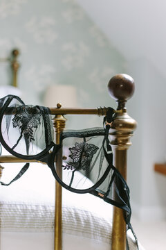 A black mesh bra draped over the end of a bed.