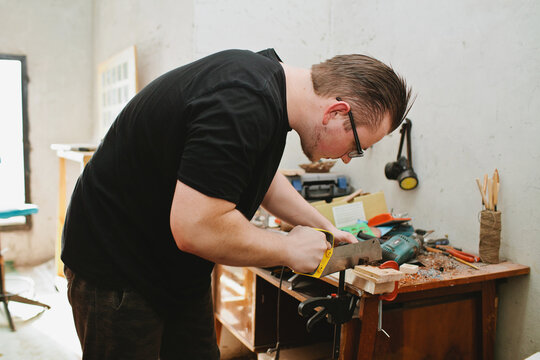 Worker sawing wood using a hacksaw