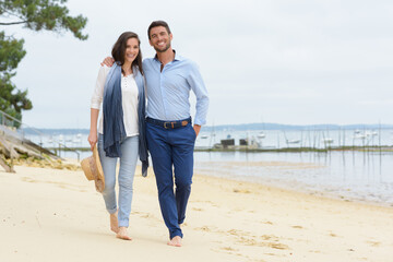 couple on casual clothing walking on beach