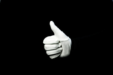 A hand wearing white glove on black background showing that everything is ok
