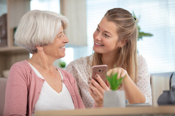 elderly woman with adult granddaughter looking at smartphone