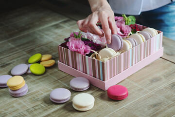 Female hand fills the decorated by delicious macaroon.