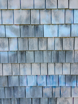 Painted blue and grey shingles on building wall, close up