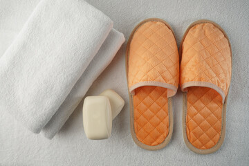 shower set in the hotel two white terry towels, soft peach slippers and two pieces of fragrant soap on a white terry mat