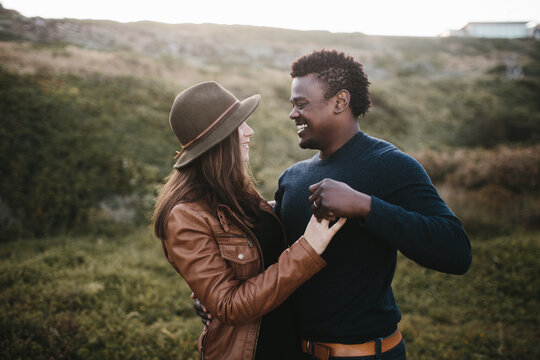 couple hugs holding hands laughing in a field