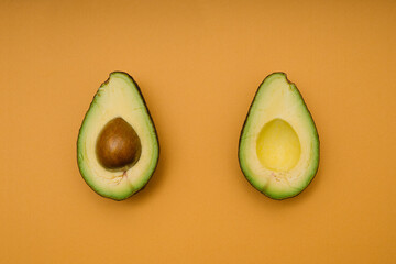 Avocado halves on orange background. Flat lay.