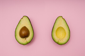 Avocado halves on pink background. Flat lay.