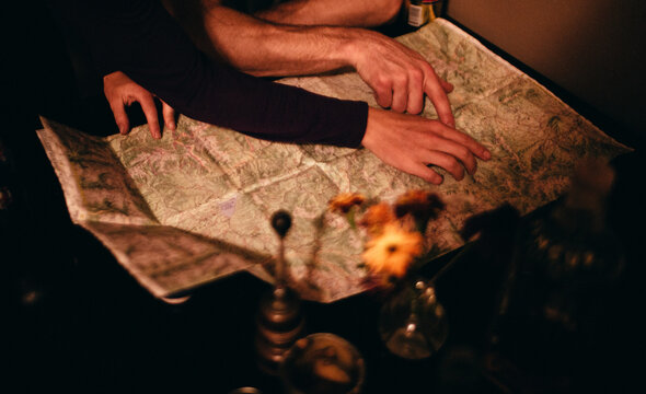 Two young adult men point at a map and plan their hunt