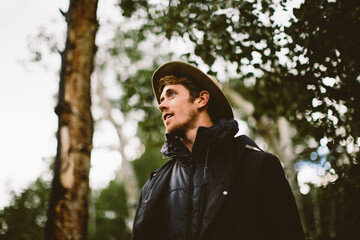 One man in black jacket gazes into distance in forest