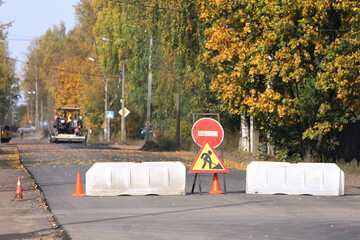 Plastic road barriers and repair work signs block access to the road section where is underway to...