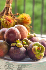 set fruit asia tropical fresh mangosteen and passion fruit lies on a plate on a background of rambutan branch